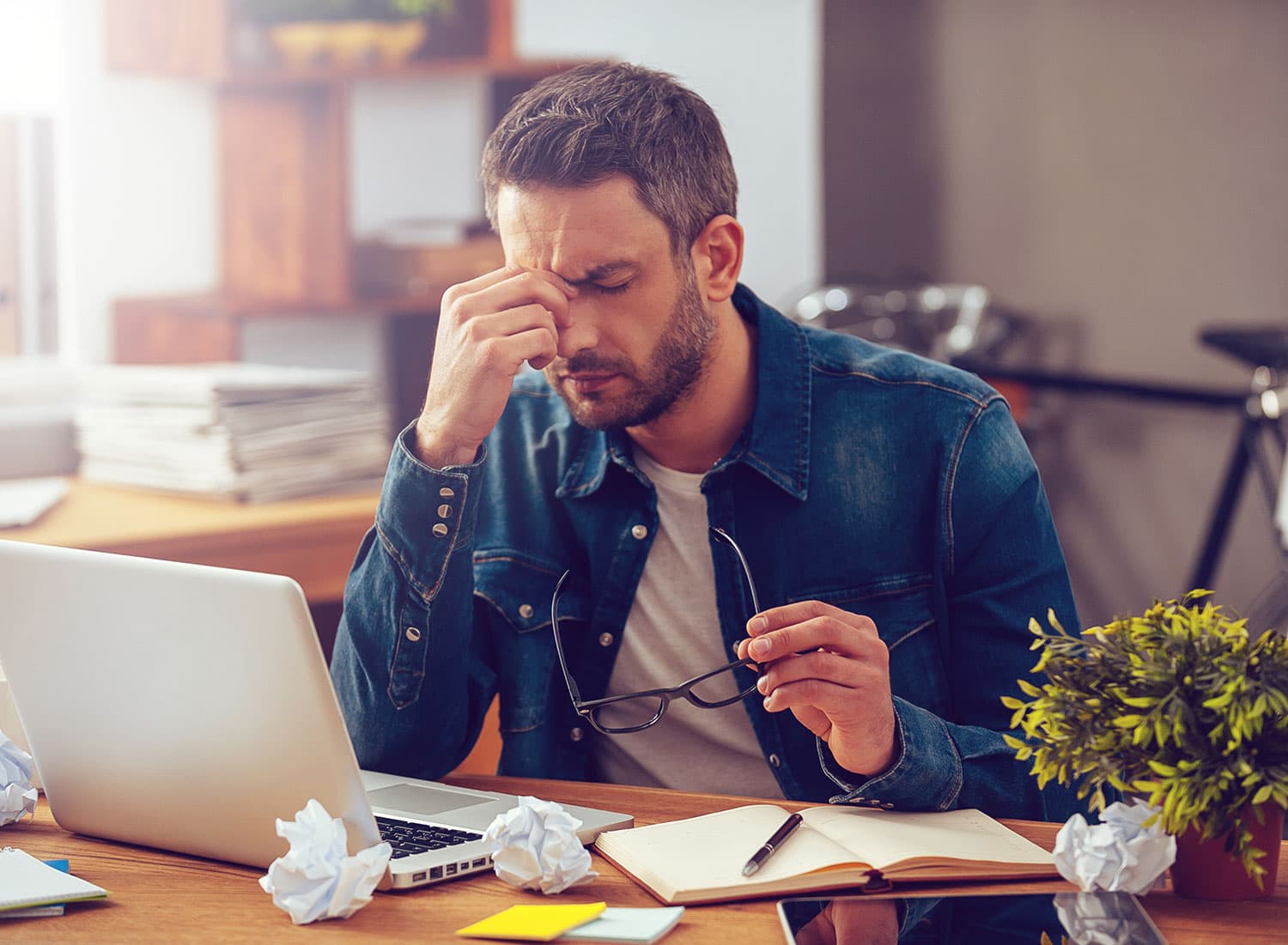 Man sitting at his laptop looking stressed and overwhelmed by his work.